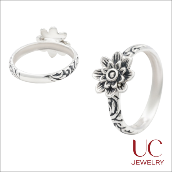 Two views of a sterling silver ring from UC Jewelry featuring a layered flower centerpiece and an engraved band with dark oxidized scrollwork accents against a white background.