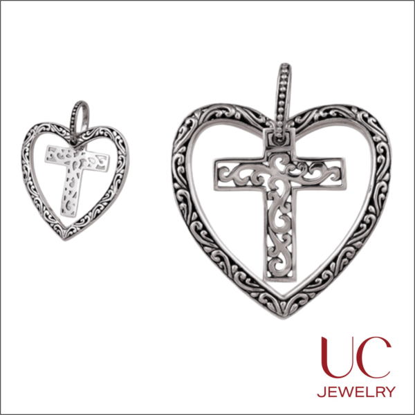 Two sizes of UC Jewelry sterling silver-toned pendants featuring an ornate filigree open heart frame with a matching decorative scrollwork cross center.
