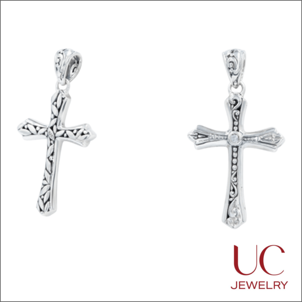 Exquisite 925 sterling silver cross pendants by UC Jewelry, featuring intricate Balinese-inspired engravings. These handcrafted pieces showcase a blend of polished finishes and oxidized scrollwork, with one design highlighting a delicate leaf motif and the other a bezel-set clear gemstone at its center. Perfect for those seeking artisanal religious jewelry with a timeless, vintage-inspired aesthetic.